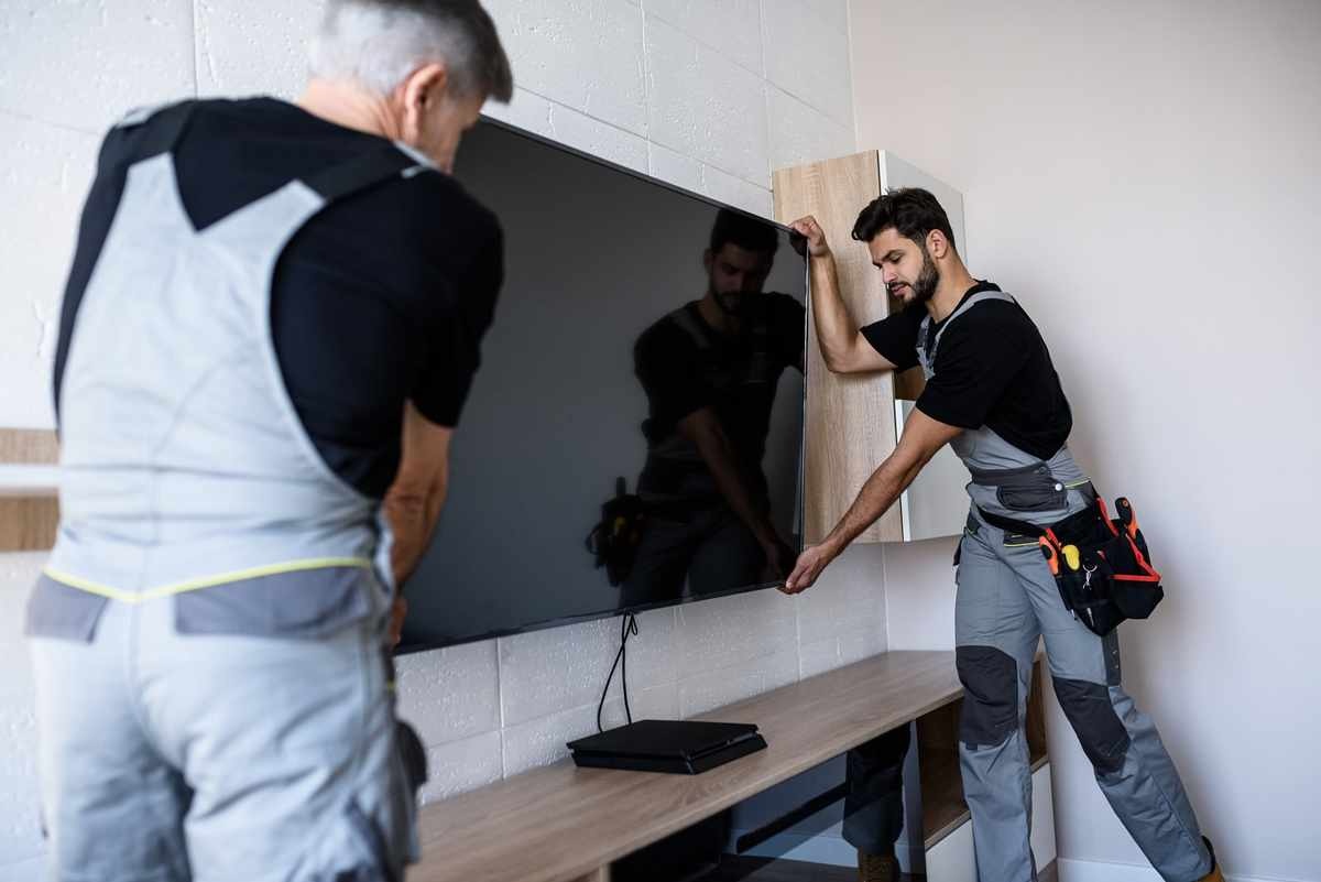 Technicians installing a wall-mounted display